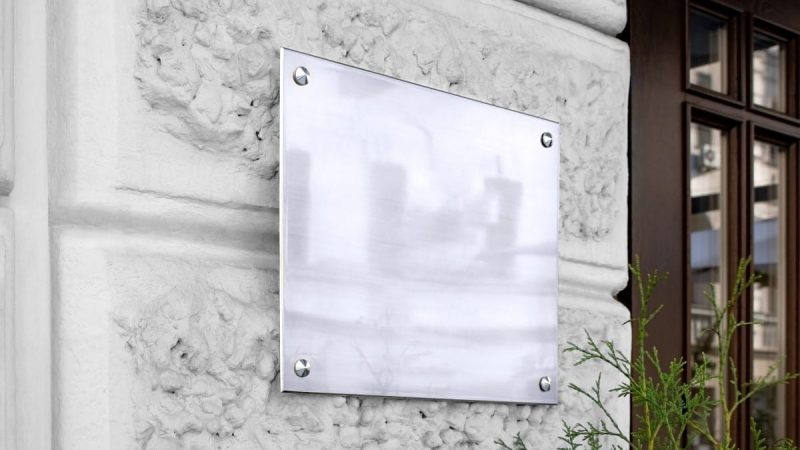 Blank silver glass signboard on textured wall mockup