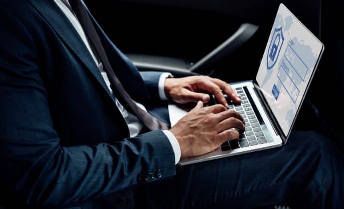 partial view of american businessman using laptop with internet security illustration in car