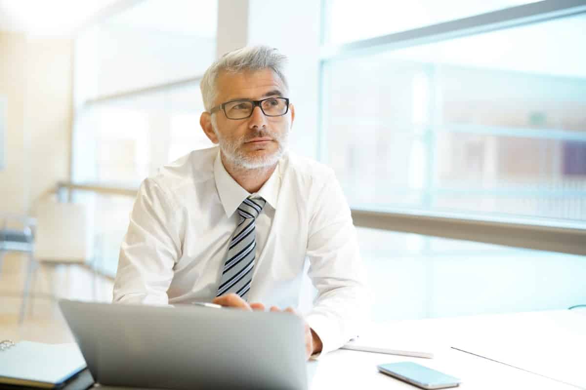Relaxed businessman thinking at desk in modern office